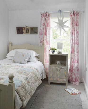Barns sovrum med rosa gardiner och böcker på golvet