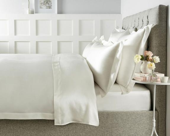 Ylellinen makuuhuone, jossa on valkoinen seinäpanelointi ja Audley puhdassilkkinen Oxford-tyynyliina reunuksella The White Companyn