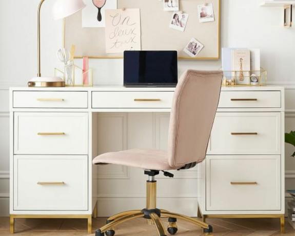 Rožinė biuro kėdė ir nešiojamas kompiuteris ant stalo