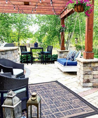 una alfombra pintada al aire libre en un área de patio con asientos en el patio y un columpio doble al aire libre