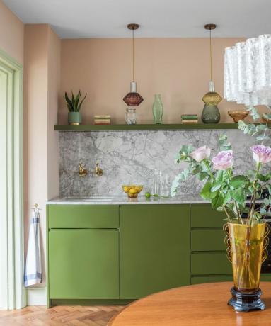 Zelené kuchynské skrinky s broskyňovými stenami a mramorovým zadným panelom