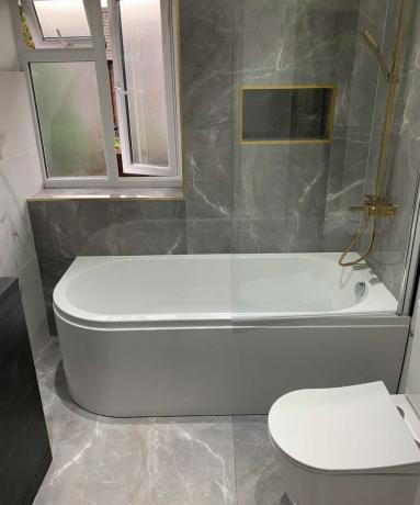 Badezimmer mit grauem Marmoreffekt mit weißer Badewanne und Toilette