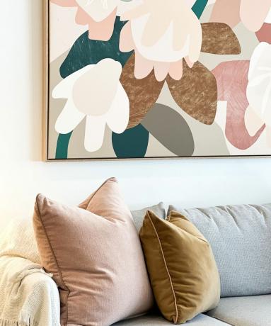 крупный абстрактный принт в теплых розовых тонах, гармонирующий с подушками на диване