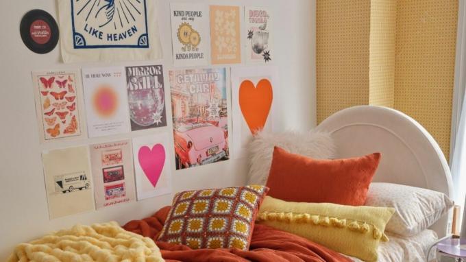 Cama naranja con galería de arte en la pared