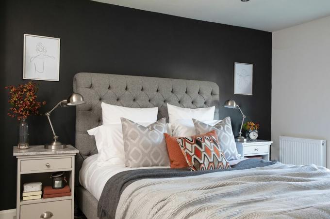 Hutchinson house: sovrum med mörk vägg och grå stoppad sänggavel