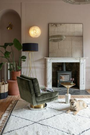 sala de estar neutral con espejo de gran tamaño en la repisa de la chimenea, lámpara de pie de silla retro, alfombra blanca y negra