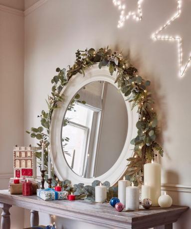 クリスマスの装飾が施されたコンソールテーブルの鏡の周りのクリスマスの花輪-Lights4Fun