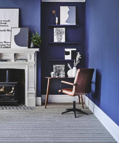 Uma sala azul cobalto com área de estudo e piso em carpete