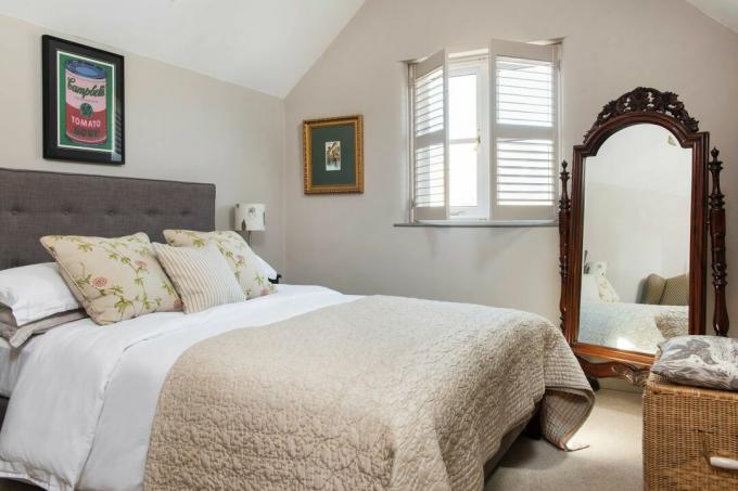 camera da letto con persiane neutre e specchio antico