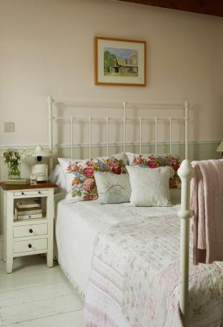 cama-vintage-com moldura de metal com-mesa-de-cabeceira-almofadas florais