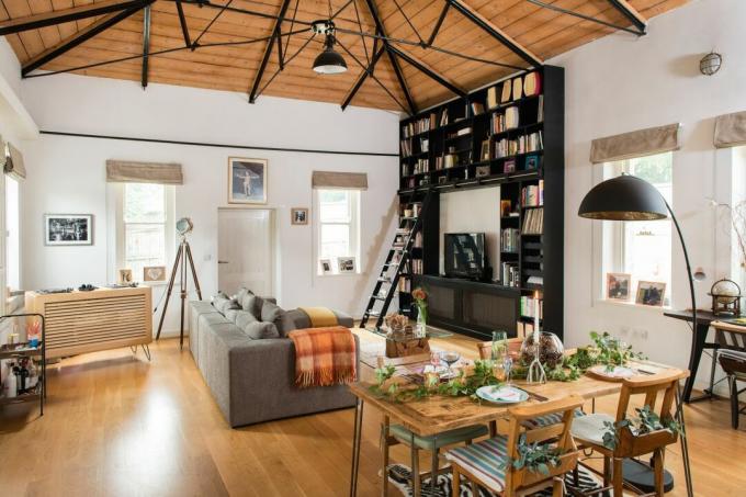 soggiorno e zona pranzo a pianta aperta con alti soffitti in legno e una libreria
