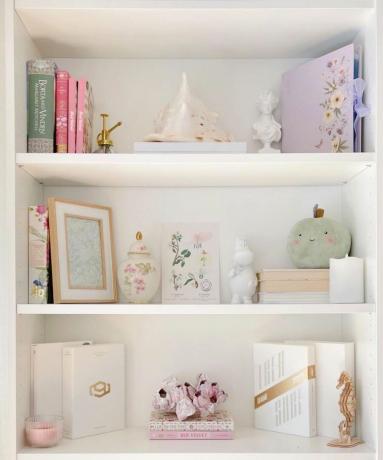 uma estante branca imaculada com livros e itens decorativos