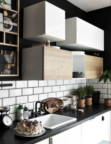 una cucina in bianco e nero con piastrelle bianche della metropolitana, controsoffitti neri e cubi di stoccaggio montati a parete con una gamma di scaffalature