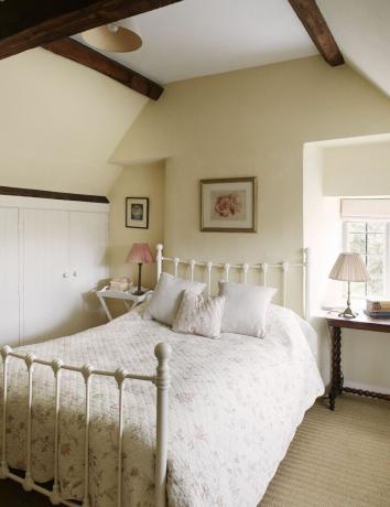 balta rāmja gulta guļamistabā ar krēmkrāsas sienām
