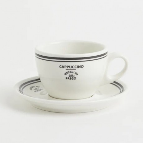 Et hvitt og svart cappuccino-krus og tallerkensett