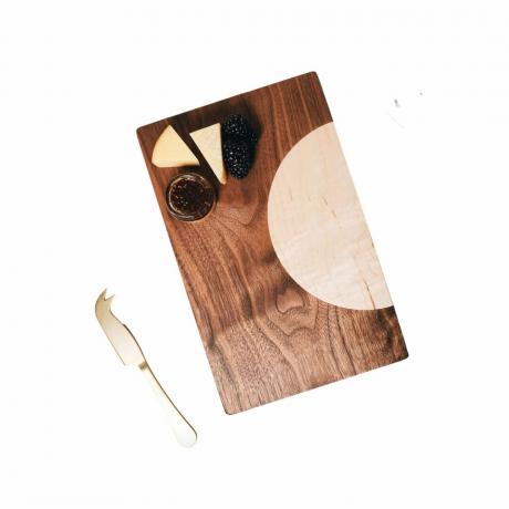 houten serveerplank met linksboven een koperen mes en linksboven kaas