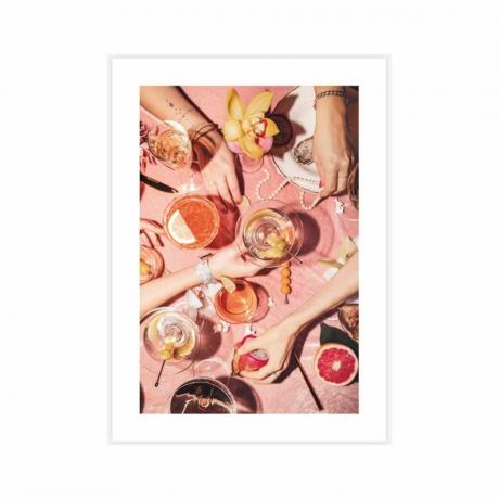 Kuva vaaleanpunaisesta ruokapöydästä, jossa on ruokaa, juomia ja käsiä