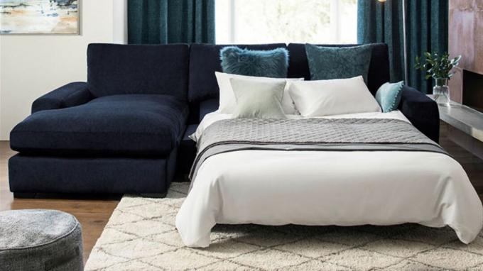 Un divano letto con chaise longue blu navy con biancheria da letto