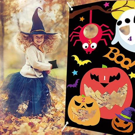 detská halloweenska hra hádzania sedacieho vaku do diery s dievčaťom oblečeným ako čarodejnica