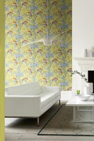 Woonkamer met witte bank, geel bloemenprintbehang en vloerkleed met geometrische print