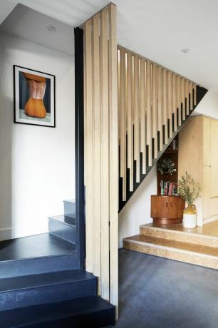 Treppe mit schwarz lackierten Stufen und raumhohem Holzlattengeländer