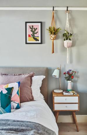 Szara sypialnia z wiszącymi roślinami domowymi