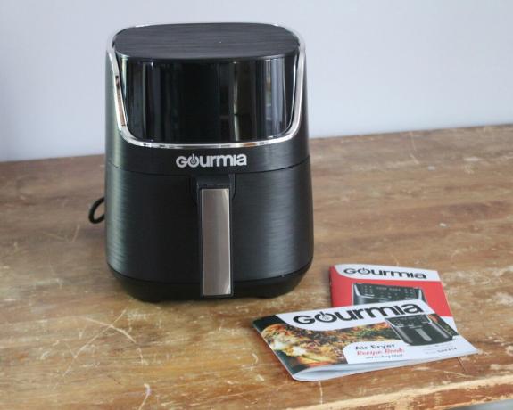 Eine ausgepackte digitale 4-Liter-Luftfritteuse von Gourmia mit Literatur auf einem abgenutzten Holztisch