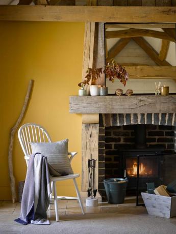 sala de estar amarilla con chimenea estilo granja, silla de madera blanca