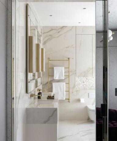 Salle de bain en marbre avec robinets dorés et support de douche