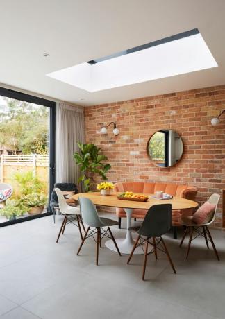 Dani Ellis'in evi: açık tuğla tarzı duvara karşı yuvarlak masalı açık plan yemek alanı