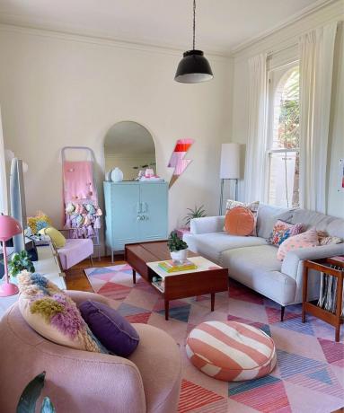 Un piccolo soggiorno con un divano grigio, un tavolino da caffè e decorazioni e mobili colorati