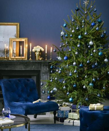 En blå juledekorasjon med fløyelslenestol og fotskammel