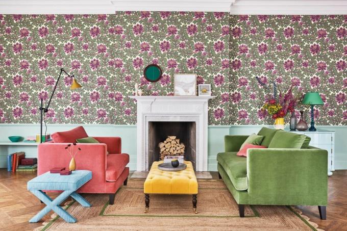 パターン化された花柄の壁紙と対照的な明るい色のベルベットのソファ