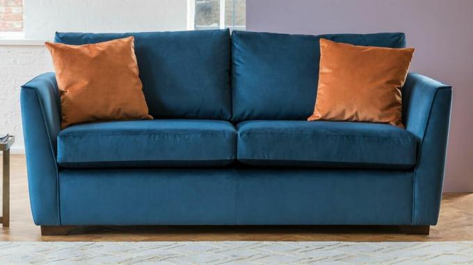 Mėlyna aksominė 3 vietų miegamoji sofa su oranžinėmis pagalvėlėmis