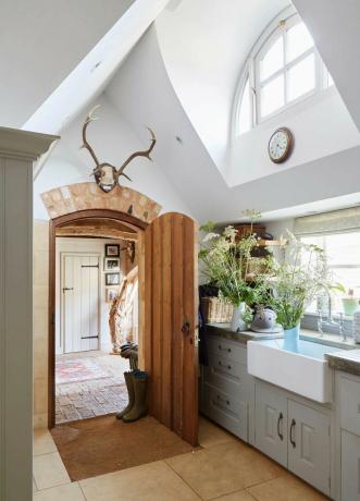 кухня в коттеджном стиле с раковиной для дворецкого и деревянной дверью