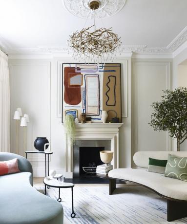 Moderne pejs med abstrakt kunst over kaminhylde og buede sofaer