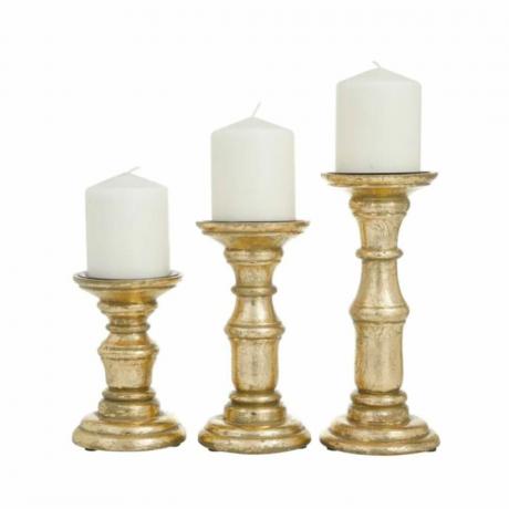Kolme kultaista kynttilänjalkaa, joissa valkoiset kynttilät