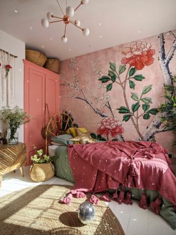 Roze bloemenbehang in slaapkamer met jute vloerkleed, moderne hangende verlichting en roze plaid