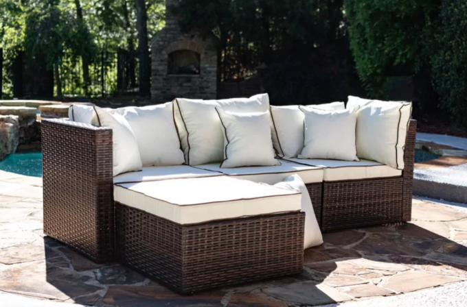 Un divano componibile effetto vimini con rivestimento color crema vicino a una piscina