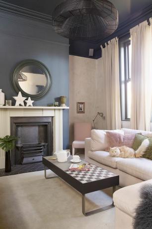 jemne ružová obývacia izba s čiernou stenou, ružovou pohovkou a konferenčným stolíkom