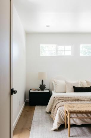 Et neutralt soveværelse med sengegavl i organisk form, neutral indretning og en række naturlige teksturer overalt