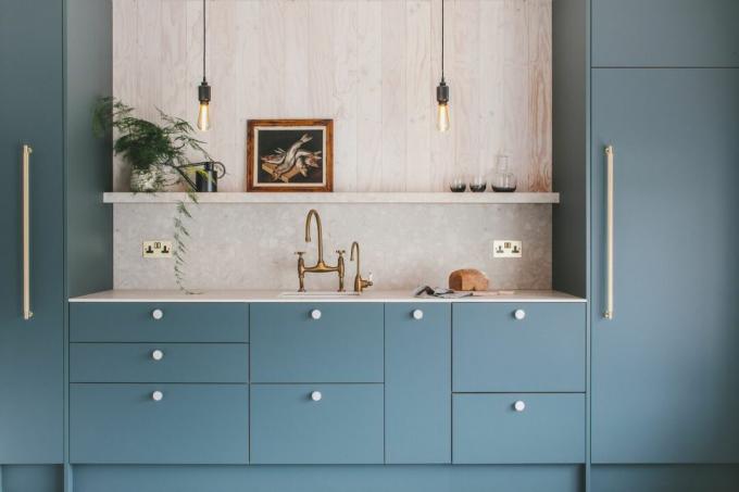 cocina con gabinetes de cocina de color azul profundo y bombillas a la vista, un ejemplo de la planificación exitosa de la cocina por parte de cáscara