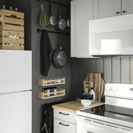 Идеја о малој кухињи са бијелим сјајним ормарима, сивим зидовима, дрвеним облогама, зидним облогама и висећим посуђем за кухање