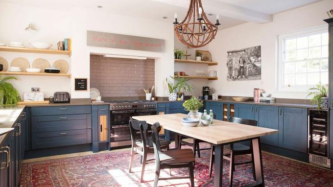 Cuisine-salle à manger avec éléments de cuisine bleu foncé et grande table au centre de la pièce