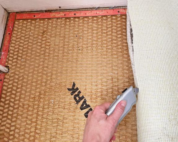 couper le côté d'un morceau de tapis enroulé pendant le retrait du tapis