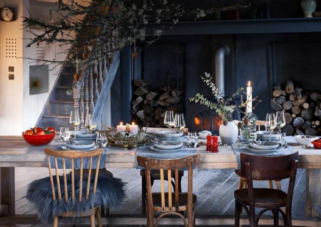 Sala festiva blu con grande tavolo da pranzo, sedie in legno e decorazioni natalizie rosse