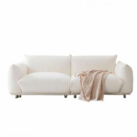 Un sofá boucle blanco con una manta beige.