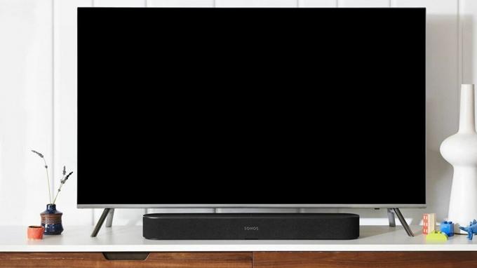 Sonos Beam na drvenom TV postolju ispred televizora