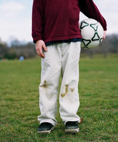 grasvlekken op witte jeans op jongen met voetbal - GettyImages-CA33547