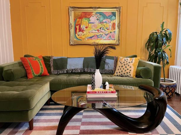 Sala de estar laranja com mesa de centro ondulada e obras de arte